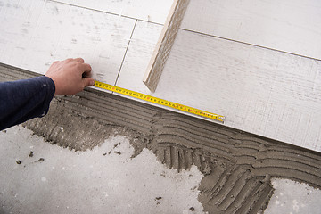 Image showing worker installing the ceramic wood effect tiles on the floor