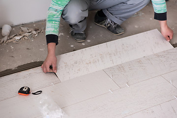 Image showing worker installing the ceramic wood effect tiles on the floor