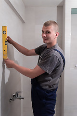 Image showing professional plumber using bubble level in a bathroom