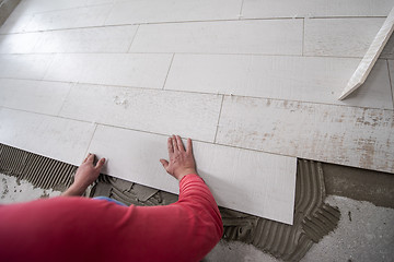 Image showing worker installing the ceramic wood effect tiles on the floor