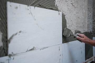 Image showing worker installing big ceramic tiles