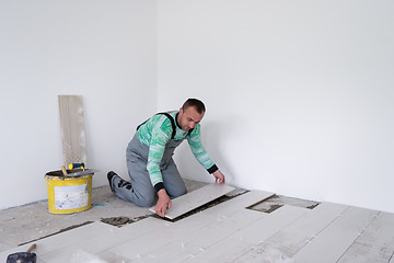 Image showing worker installing the ceramic wood effect tiles on the floor