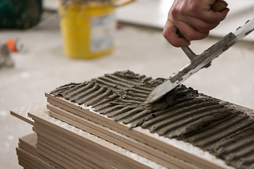 Image showing worker installing the ceramic wood effect tiles on the floor