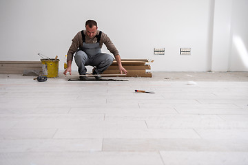 Image showing worker installing the ceramic wood effect tiles on the floor