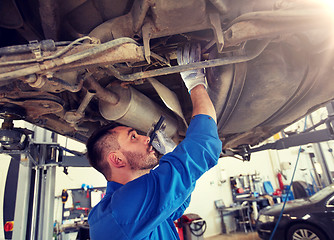 Image showing mechanic man with flashlight repairing car at shop