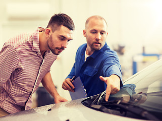 Image showing auto mechanic with clipboard and man at car shop