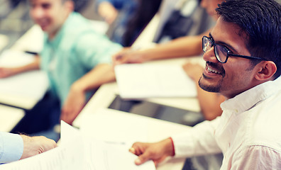 Image showing happy student with exam test or handout at lecture