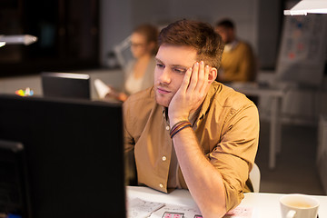 Image showing tired or bored man with computer at night office