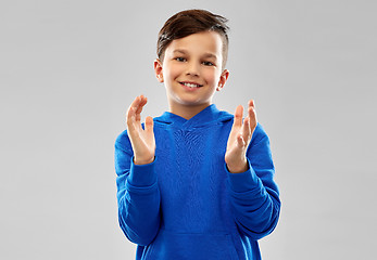 Image showing portrait of smiling boy in blue hoodie applauding