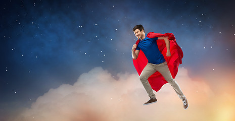 Image showing man in red superhero cape flying over night sky