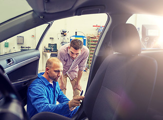 Image showing mechanic and man checking seat belt at car shop