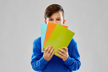 Image showing shy student boy hiding behind books