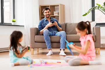 Image showing father with smartphonew and daughters at home