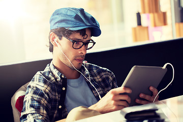 Image showing man with tablet pc and earphones sitting at cafe