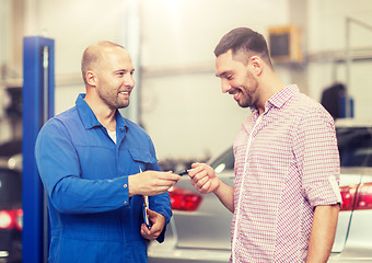 Image showing auto mechanic giving key to man at car shop