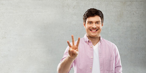 Image showing man showing three fingers over gray concrete wall