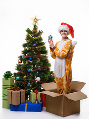 Image showing The girl stands in a box of Christmas tree toys dressing up the Christmas tree and looked cheerfully in the frame