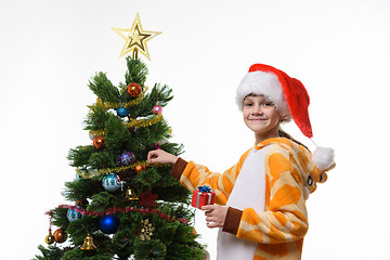 Image showing Eight-year-old girl dresses up Christmas tree, portrait