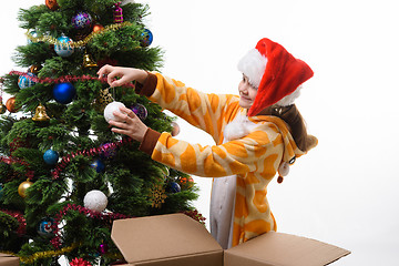 Image showing Girl pulls out of the box Christmas tree ball and hangs on the Christmas tree