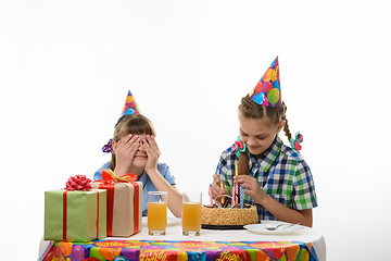 Image showing A girl puts candles on a birthday cake, the other closed her eyes