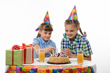 Image showing children light candles with a match on the cake, at the table at the birthday party