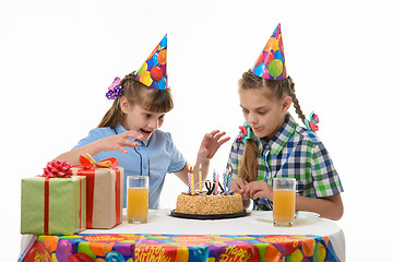 Image showing Two girls want sweet and are happy to throw themselves on a birthday cake
