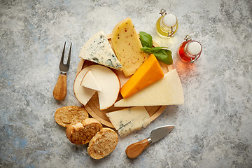 Image showing Various types of cheese served on rustic wooden board