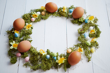 Image showing Colorful decorative Easter eggs wreath on white wooden table background