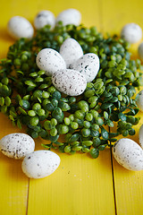 Image showing Green decorative Easter quail eggs wreath on yellow wooden table