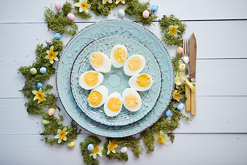 Image showing Easter table setting with flowers and eggs. Decorative plates with boiled eggs