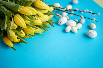 Image showing Holiday contept decoration with easter eggs and yellow tulips over blue