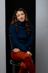 Image showing Funny cute girl sits on a chair on a black and gray background