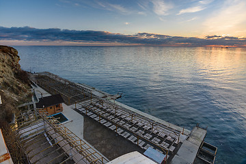 Image showing Sunset view on an empty sunlounge beach on a rocky sea shore