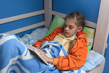 Image showing Sick girl reads a book lying in bed in bed