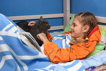 Image showing The girl rejoices in the cat who came to her bed