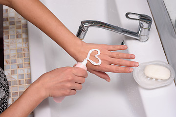Image showing Girl puts heart shaped cream on hands