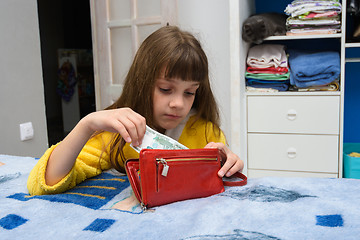 Image showing The girl opened her mothers wallet and pulls out a thousand-ruble note
