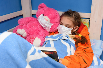 Image showing Girl and plush toy in medical masks in bed read a book