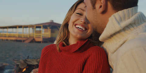 Image showing Loving Young Couple Sitting On The Beach beside Campfire drinkin