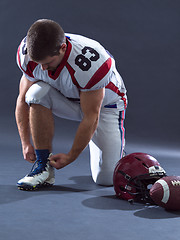 Image showing American Football Player tie his shoe laces isolated on gray