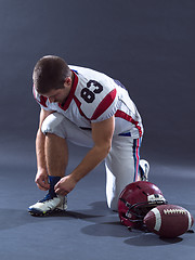 Image showing American Football Player tie his shoe laces isolated on gray