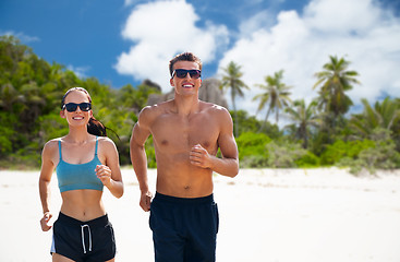 Image showing couple in sports clothes running along on beach