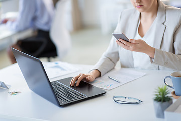 Image showing businesswoman with smartphone and laptop at office