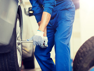 Image showing mechanic with screwdriver changing car tire