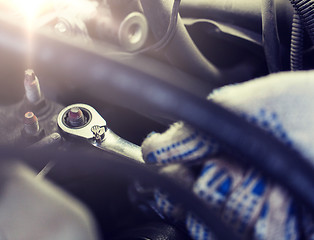 Image showing mechanic man with wrench repairing car at workshop