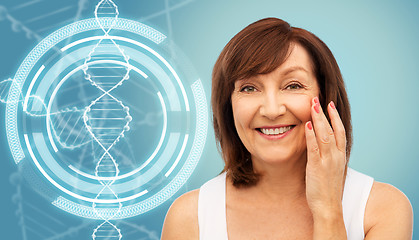 Image showing senior woman touching her face over dna molecule