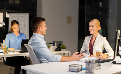 Image showing business people drinking coffee at night office