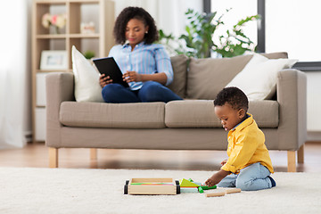 Image showing baby playing toy blocks and mother using tablet pc