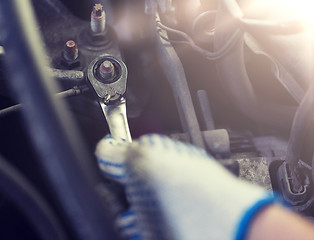 Image showing mechanic man with wrench repairing car at workshop