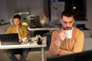 Image showing happy male office worker drinking coffee